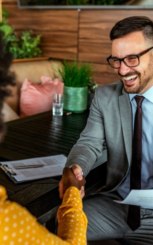 Finishing up a conversation after collaboration, handshake of two business people, male and female, after contract agreement to become a partner, collaborative teamwork. Female Manager interviewing a male applicant in her office while sitting during the day.